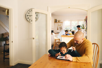 Multiracial father and son with Down syndrome using digital tablet
