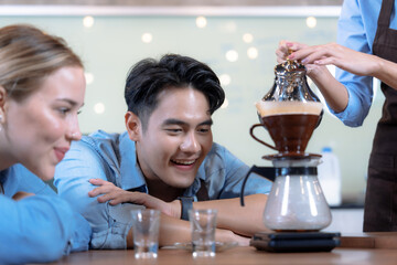 Male and female students learn to brew coffee in barista school.