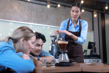 Male and female students learn to brew coffee in barista school.