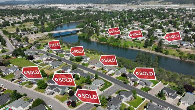 Drone shot of SOLD signs popping up over recently sold houses in a suburban neighborhood.