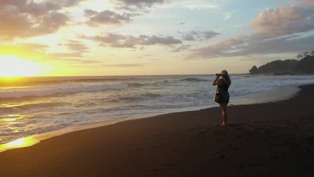 Woman taking photos at beach during sunset in tropics