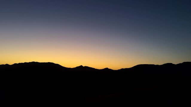 Dark mountain silhouette landscape with colourful sunset sky in desert