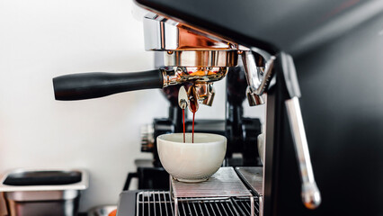 Coffee extraction from the coffee machine with a portafilter pouring coffee into a cup,Espresso poruing from coffee machine at coffee shop