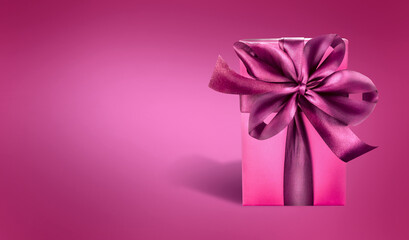 Beautiful greeting background with dark pink gift box with silk bow, front view. 