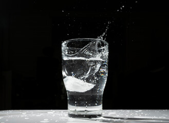 the scene of an ice cube falling into a cup