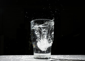 the scene of an ice cube falling into a cup