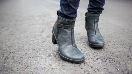 Young woman wearing nice boots standing on the asphalt surface.