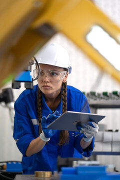 Robotic maintenance engineer working on robot arm connection using tablet computer. Smart women learning training industry 4.0 robotic engineering in futuristic electronic technology academy workshop