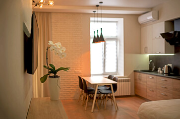 Open plan living room and kitchen interior with white cabinets, table and chairs