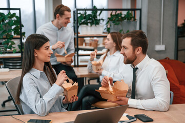 Casual conversation. Group of coworkers are eating food from eco boxes in the office together