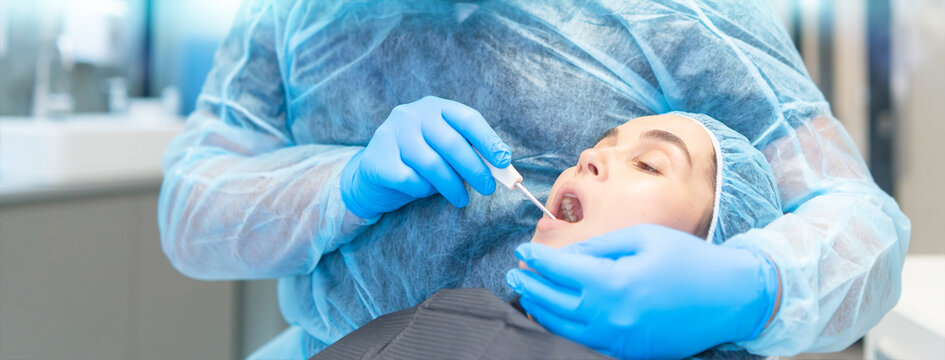 Male dentist with female patient in dental chair providing oral cavity treatment.