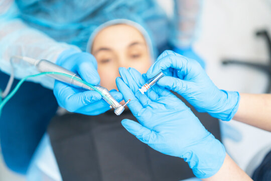 Closeup photo of dental implant in dentist hands with female patient in dental chair behind.