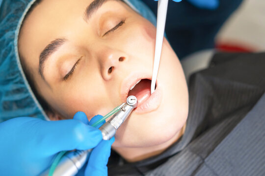 Closeup photo of male dentist with female patient in dental chair providing oral cavity treatment.