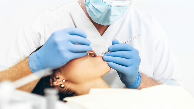Dentist with patient in dental chair providing manipulations in oral cavity.