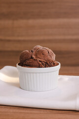 Cup of chocolate ice cream on a wooden table.