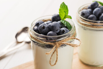 Homemade Greek yogurt in a glass jars on white wood table ready to eat. Healthy breakfast. Superfoods. Macro with shallow dof.