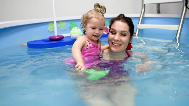 Happy mother swims in the pool with her daughter
