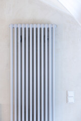 Eine Heizung bzw. ein grauer, moderner Heizk&ouml;rper vor einer Betonwand in einem energetischen sanierten Altbau