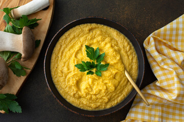 Mushroom cream soup in a plate, delicious healthy Eringi mushroom soup, fresh mushrooms on a cutting board, top view