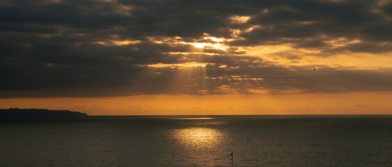 Naklejka na ściany i meble Coastal sunset with clouds and golden sky