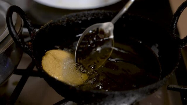 View Of Metal Slotted Spoon Gently Moving Floating Fresh Guror Handesh In Hot Oil. Slow Motion