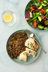 Healthy breakfasts, wild rice with chicken breast and goat cheese with greens, mix salad with cucumbers and tomatoes, top view