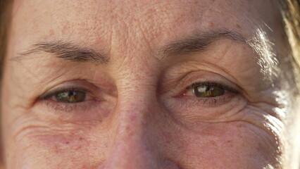 Macro close up of senior woman closing eyes in contemplation. Older female person in 70s opening...