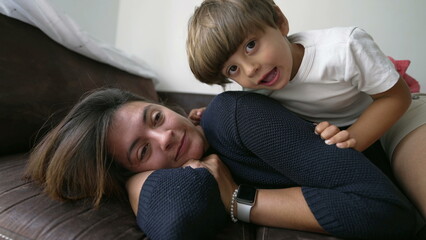 Mother and child son lying on sofa couch together. Lifestyle concept of parent and kid at home