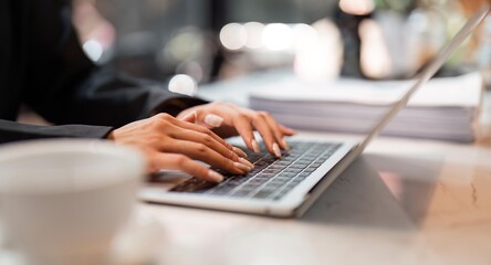 Closeup image of a business woman's hands working and typing on laptop keyboard on table