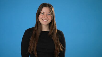 Portrait of happy smiling young brunette woman 20s wears black shirt isolated on plain blue background copy space studio portrait. People emotions lifestyle concept