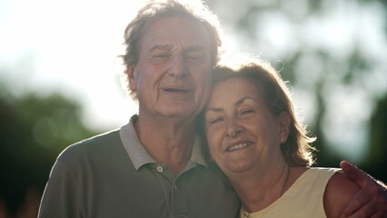 Happy senior couple posing for camera standing in nature. Older husband embracing wife smiling. 70s people