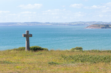 Enorme croix en granit, paysage breton, mer bleue 