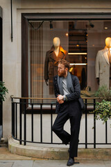 Portrait of a stylish bearded man against the background of elegant clothing store window