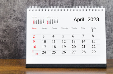 The April 2023 Monthly desk calendar for 2023 year on wooden table.