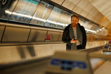 Bearded man with a smartphone on an escalator in the subway