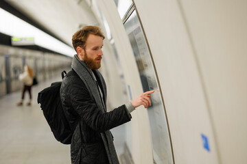 Bearded man looks at a subway train map