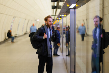 Fototapeta premium Bearded man waits for the door to open on the subway station platform to enter the train