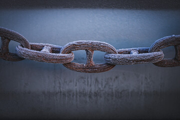 A link of an old anchor chain covered with frost. located on the shore near the old shipyard