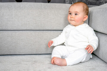 childhood, babyhood and people concept - happy little baby boy or girl sitting on floor at home