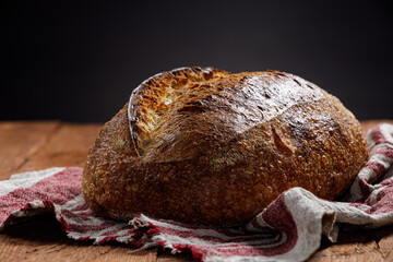 Rustic sourdough bread on a linen towel on a wooden background