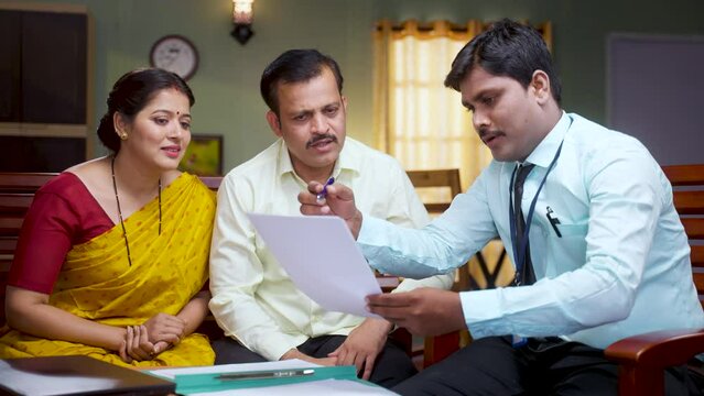 Bank officer advising or explaining about insurance policy papers to couple at home - concept of future planning, consultant and retirement planning.