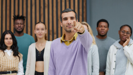 Young businessman points his index finger at the camera.