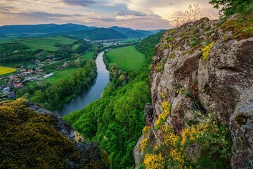 Fototapeta na wymiar Spring landscape with blooming fields, green meadows and a meandering river in a valley under rocks. Discover the beauty of spring hiking