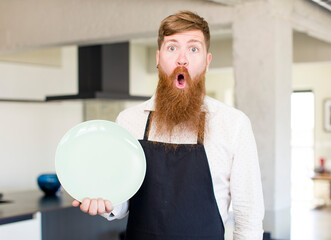 red hair man feeling extremely shocked and surprised with an empty dish. chef concept