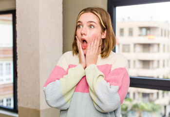 pretty caucasian woman feeling happy, excited and surprised, looking to the side with both hands on...