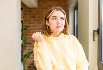 Fototapeta premium pretty caucasian woman looking confident, angry, strong and aggressive, with fists ready to fight in boxing position. home interior concept