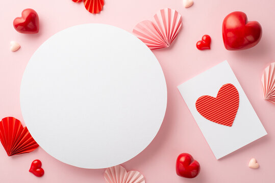 Valentine's Day celebration concept. Top view photo of white circle pink red origami paper hearts and postcard on isolated pastel pink background with blank space