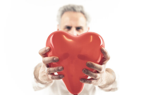 A romantic grey-haired man holding a heart-shaped balloon. Man in love - Isolated on white background. High-quality photo