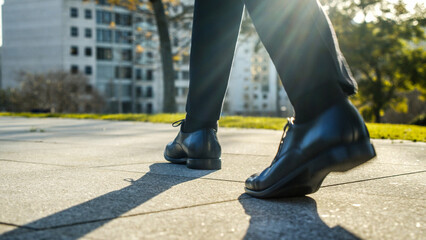 Legs of a businessman in fashionable shoes walking outdoors. Business concept. Close-up view to the businessman in a black new shoes walks on the street. Stylish men wears. Low angle. Rear view.