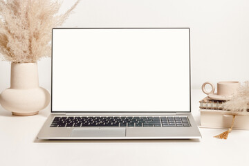 Mockup laptop with white screen on the table with vase, pampas grass and decorations. Aesthetic background for study, cozy home office, promotion, social media - obrazy, fototapety, plakaty